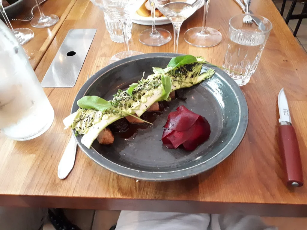 Kötträtt med rödbetspuré och örter på grå tallrik