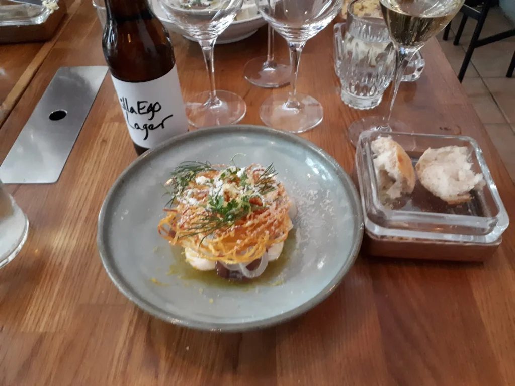 Sillförrätt på grå tallrik vid ett bord på Lilla Ego